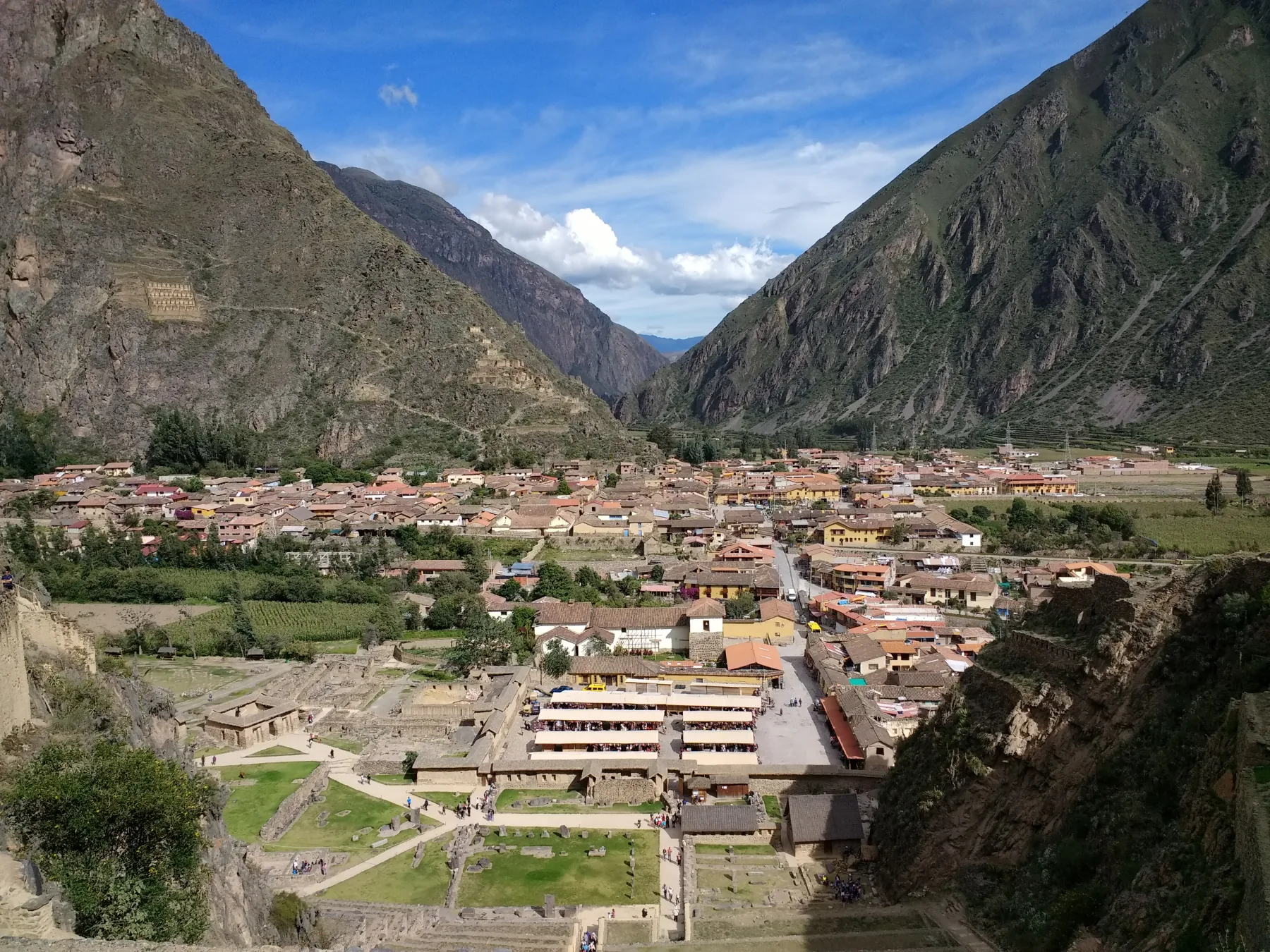 Daken van Ollantaytambo achter stenen terrassen, met bergen rondom het dorp.